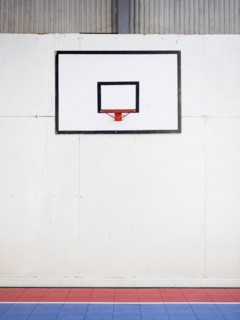 Empty basketball court with basketball hoop hanging on wall