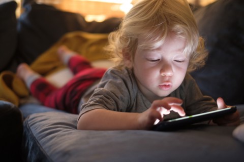 Little boy (2-3) lying on front and playing game on smart phone