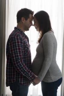 Mid adult couple in front of window, face to face
