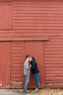 Couple kissing in front of red barn