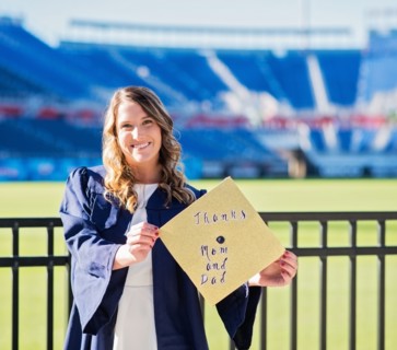 Portrait of graduate student showing message on mortarboard