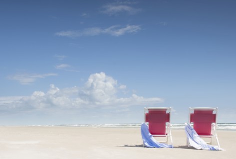 Deck chairs with towels on sandy beach by Atlantic Ocean