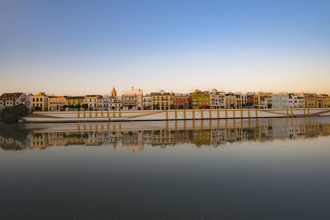 Spain, Seville, Colorful residential building reflecting in Guadalquivir river