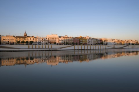 Spain, Seville, Colorful residential building reflecting in Guadalquivir river