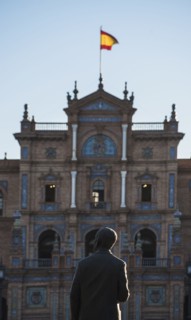 Spain, Andalusia, Seville, Facade with spanish flag and statue of Anibal Gonzales in Plaza de Espana