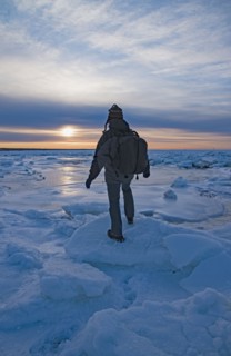 USA, Massachusetts, Cape Cod, Eastham, Man balancing on sea ice at dusk