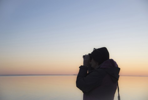 Senior woman birdwatching at sunset