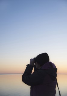 Senior woman birdwatching at sunset