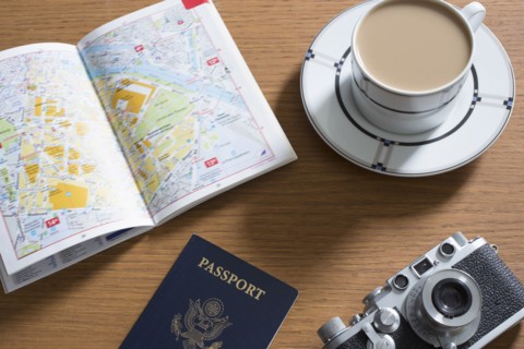 Passport, coffee, old camera and open guidebook