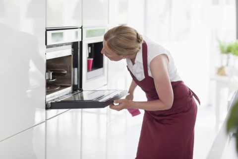 Woman using oven in kitchen