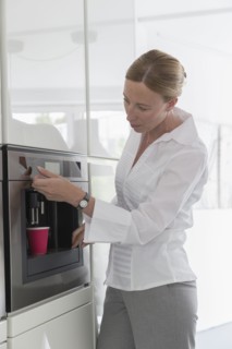 Mature woman preparing coffee in modern kitchen
