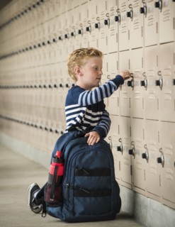Boy with backpack by school lockers