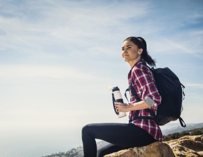 Woman with water bottle sitting on rock