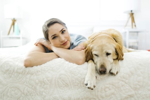Woman lying on bed with dog