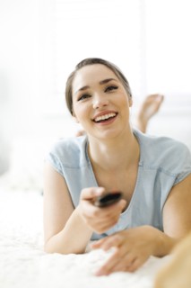 Woman using remote control on bed