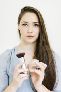 Woman holding powder and make up brush