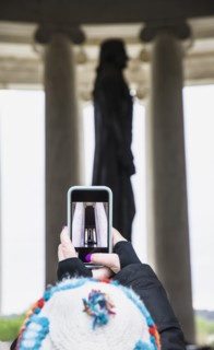Woman taking photograph of statue with smart phone