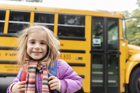 Smiling girl by school bus