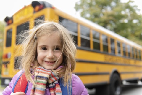 Smiling girl by school bus