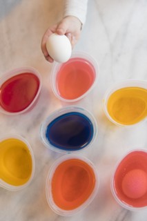 Hand of girl selecting dye for Easter egg