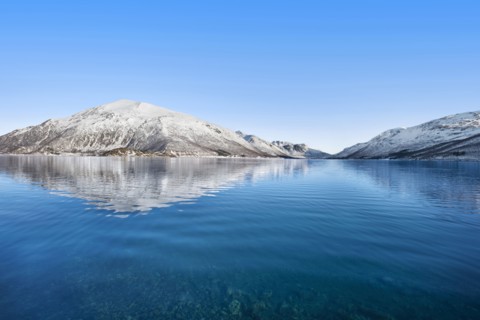 Snow covered hills by sea in Tromso, Norway
