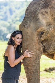 Woman holding trunk of Indian elephant in Chiang Mai, Thailand