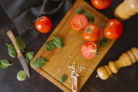 Tomatoes, basil and salt on wooden cutting board