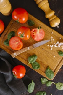 Tomatoes, basil and salt on wooden cutting board