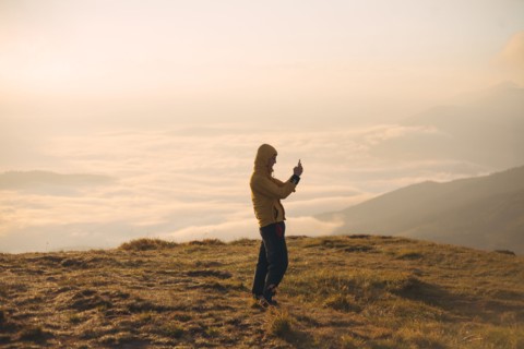Man in yellow jacket taking photograph on smart phone in the Carpathian Mountain Range