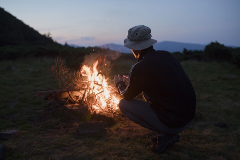 Man crouching by campfire