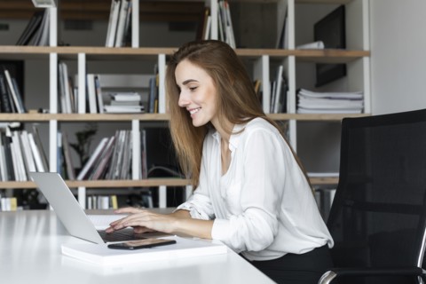 Smiling businesswoman working on laptop