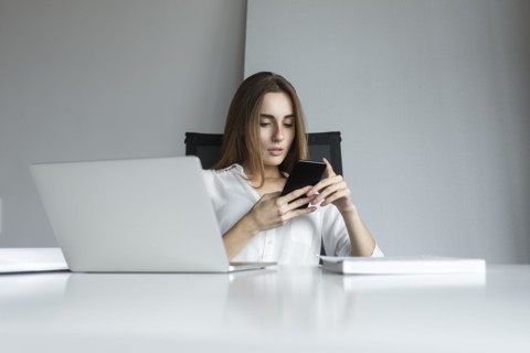 Young businesswoman text messaging at desk