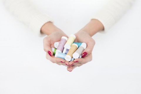 Hands of woman holding spools of cotton