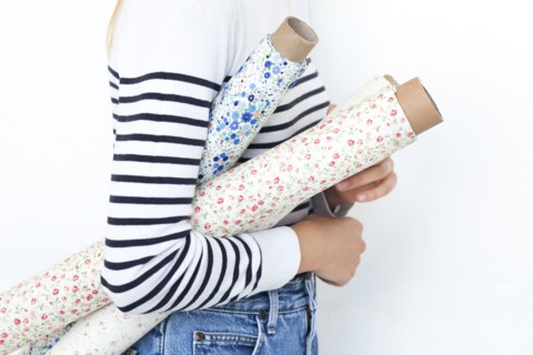Arm of woman holding rolls of floral pattern fabric