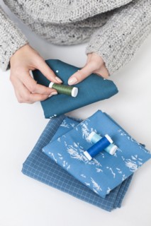 Woman's hand matching thread to blue fabric