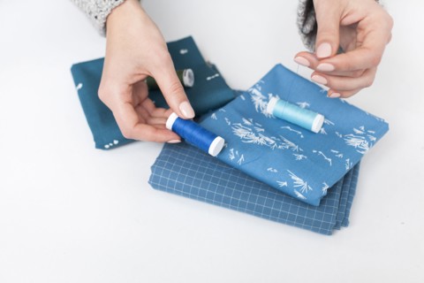 Woman's hand matching thread to blue fabric