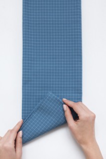 Hands of woman folding checked blue fabric