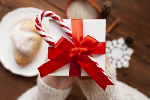 Hands of woman holding Christmas present with candy cane
