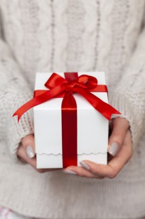 Hands of woman holding Christmas present with candy cane