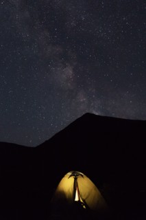 Illuminated tent by mountain at night