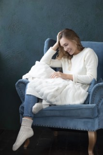 Smiling woman witting in armchair with white blanket