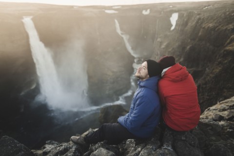 Hiker couple sitting on cliff by Haifoss waterfall in Iceland