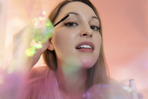 Young woman applying mascara