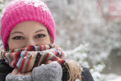 Portrait of young woman wearing woolly hat and scarf in snow