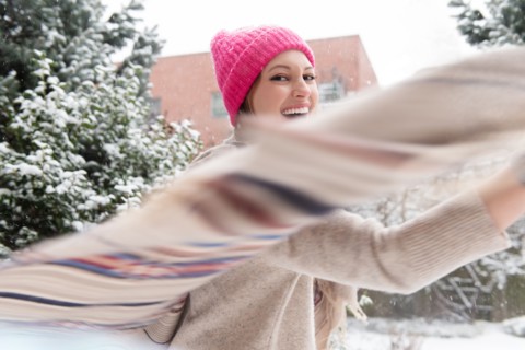 Young woman twirling with shawl in snow