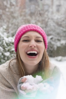 Laughing young woman holding snow