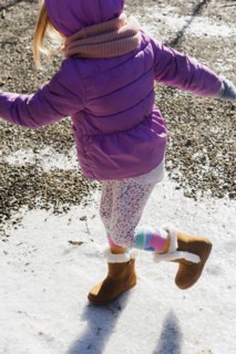 Girl wearing purple coat walking on snow