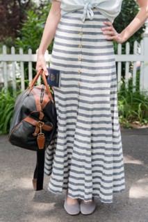 Woman wearing striped dress holding bag and passport