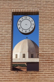 Dome behind brick window with clock in Marrakesh, Morocco