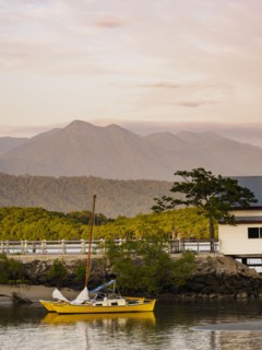 Yellow sailboat on beach at sunset in Port Douglas, Australia